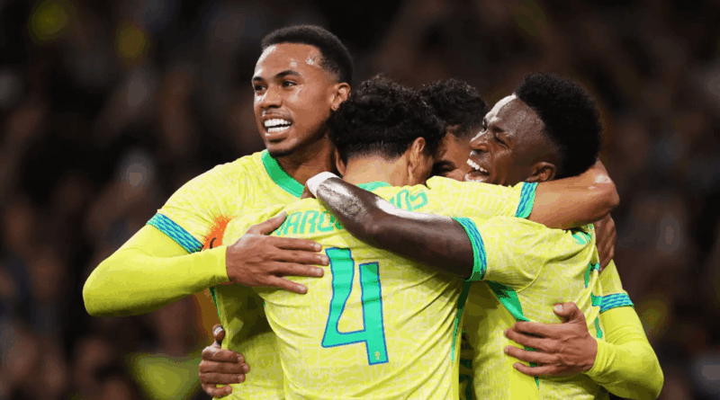 Grupo de jogadores da seleção brasileira, usando uniforme amarelo fluorescente, se abraça em comemoração dentro de campo, sorrindo e celebrando após um gol.