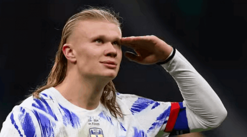 Jogador de futebol com cabelo longo loiro faz um gesto de continência com a mão direita na testa, usando a camisa branca com detalhes em azul da seleção da Noruega e a braçadeira de capitão no braço esquerdo, celebrando em campo. Jogo contra a Itália.